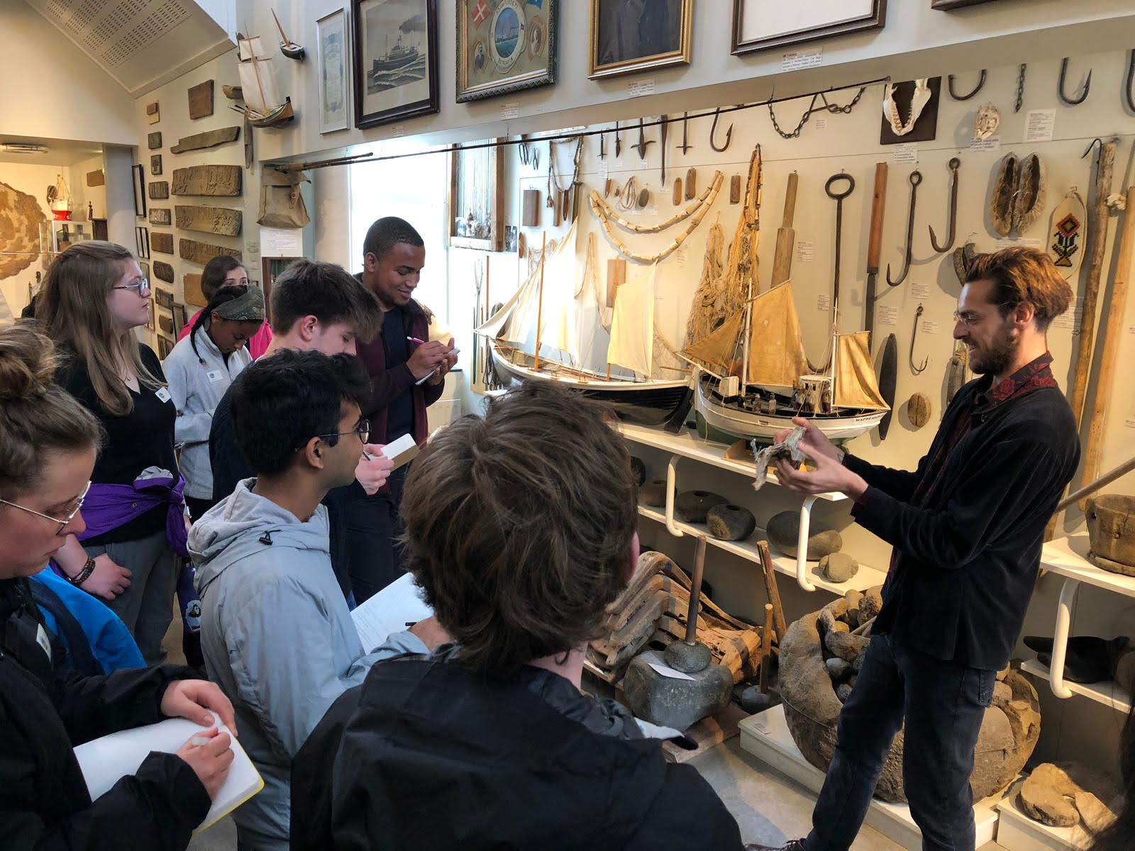 museum worker shows fishing equipment to students