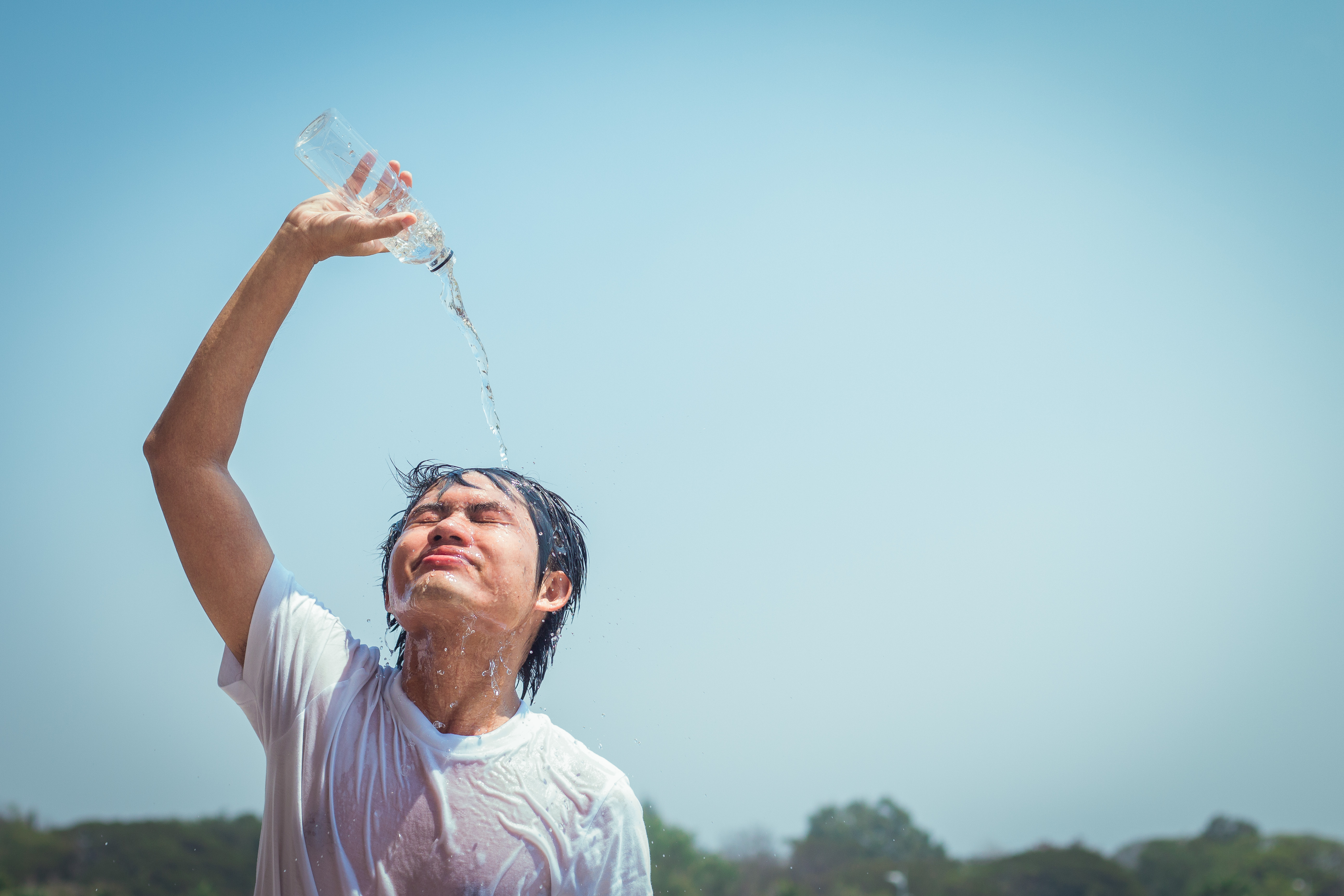 young person using a water bottle to refresh under the heat