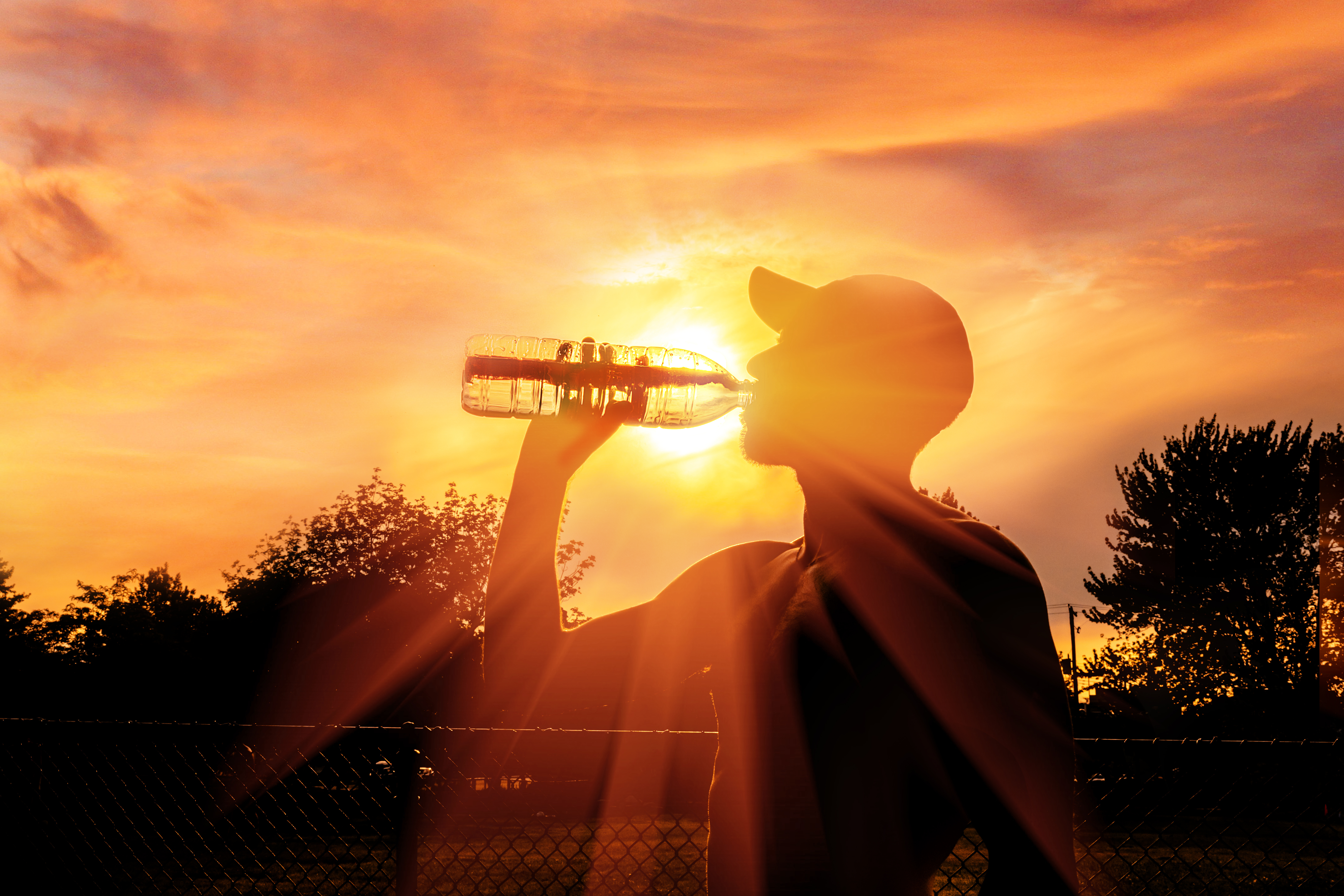 young person drinking water while the sun is setting