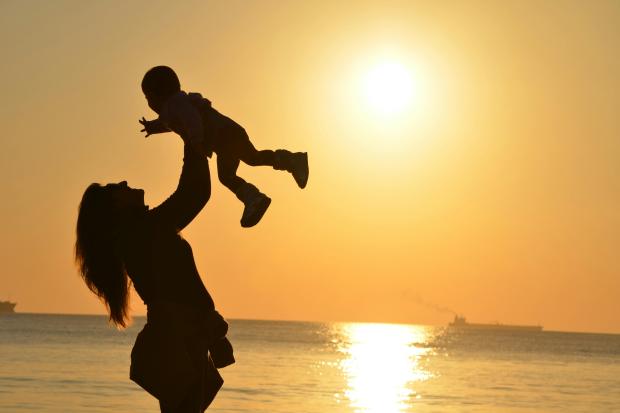 Mother with child silhouette against a sunset. 