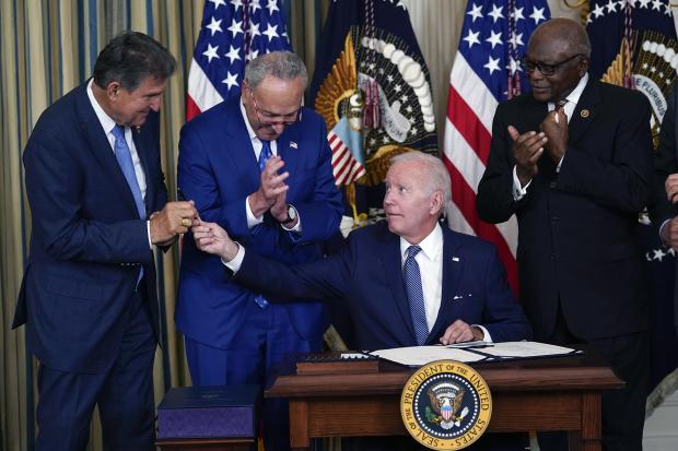 President Joe Biden hands the pen he used to sign the Democrats’ landmark climate change and health care bill to Sen. Joe Manchin (D-WV) in the State Dining Room of the White House in Washington, Tuesday, Aug. 16, 2022. (Image: AP Photo/Susan Walsh)