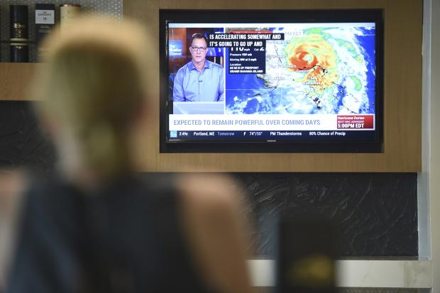 A person watching a news channel showing a weather map.