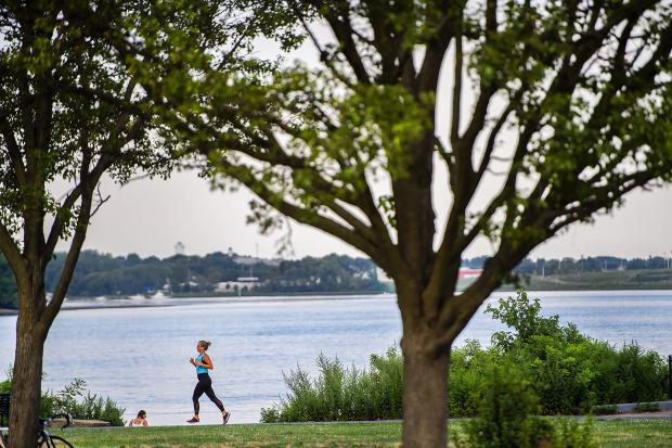 Person running along Delaware River under trees