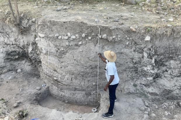 R. Ramesh adjusts measuring tape at archaeological site.