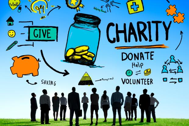 a group of people stands under a diagram of philanthropic options such as charity, volunteering, and donating