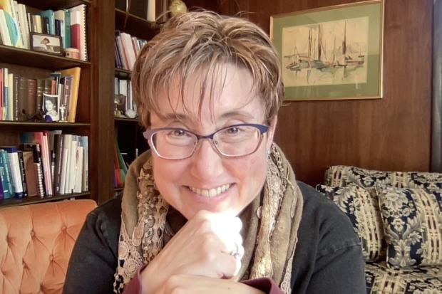 woman with glasses and books in background