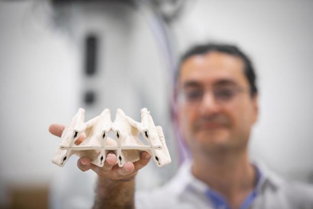 Masoud Akbarzadeh holding up one of the fabricated materials.