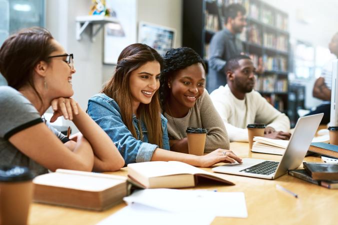 three female students seated in a row near a laptop