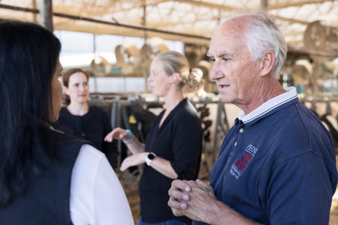Four scientists speak in a dairy cow facility