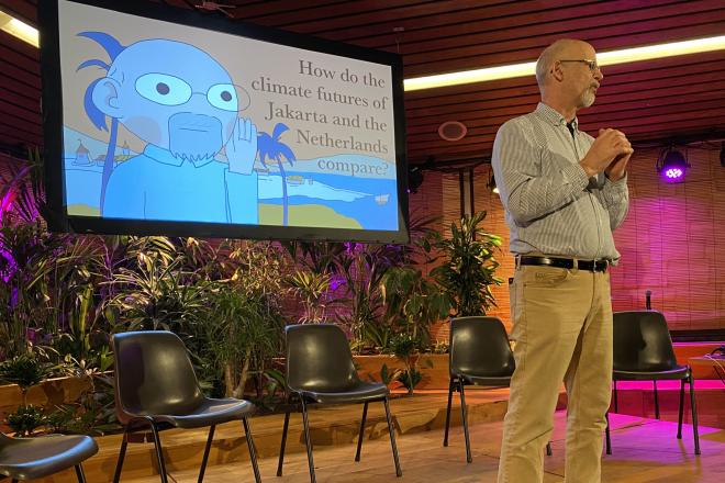 Simon Richter on stage with a video screen with an animation behind him addressing an audience.
