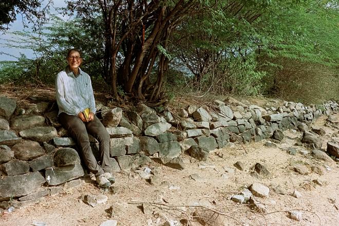 Professor Kathleen Morrison sitting on low wall outside