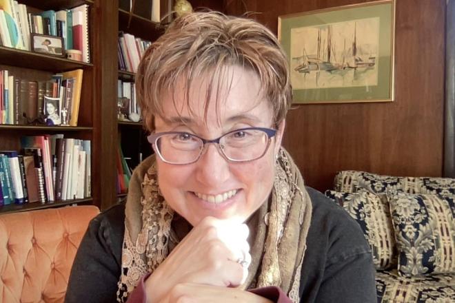 woman with glasses and books in background