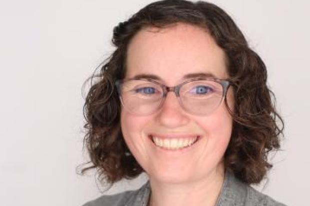 woman with dark hair and eyeglasses wearing a grey sweater