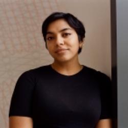 woman in dark blouse standing against wall