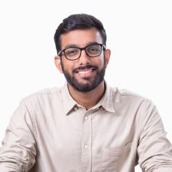 man with dark hair and beard in light colored shirt